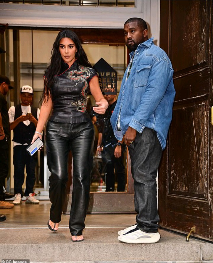 Kanye West proudly plugs new clothing creations by brandishing