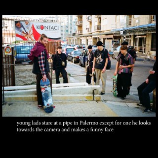 young lads stare at a pipe in Palermo except for one he looks towards the camera and makes a funny face